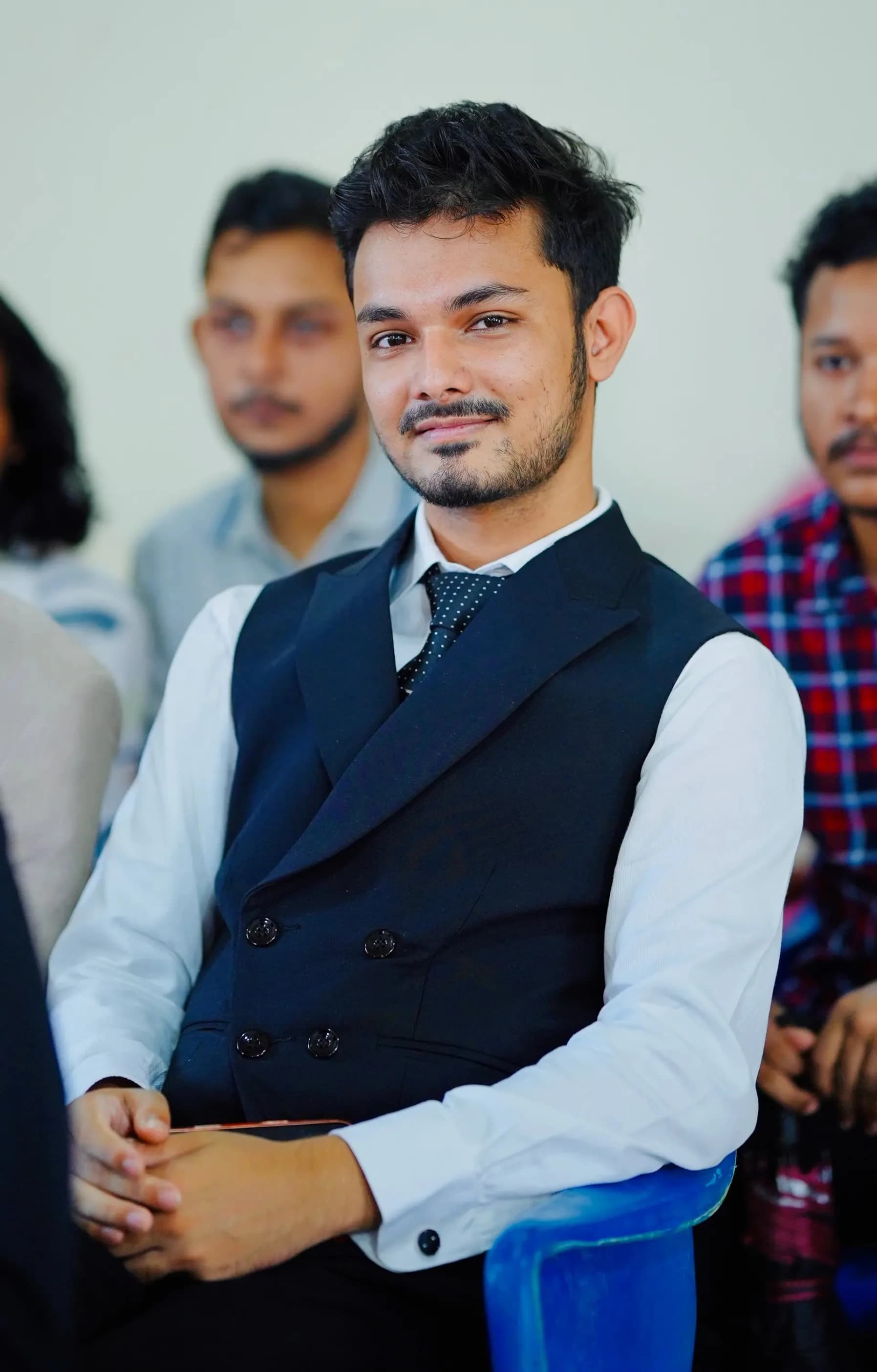 Redwan Ahmed wearing a navy waistcoat and tie